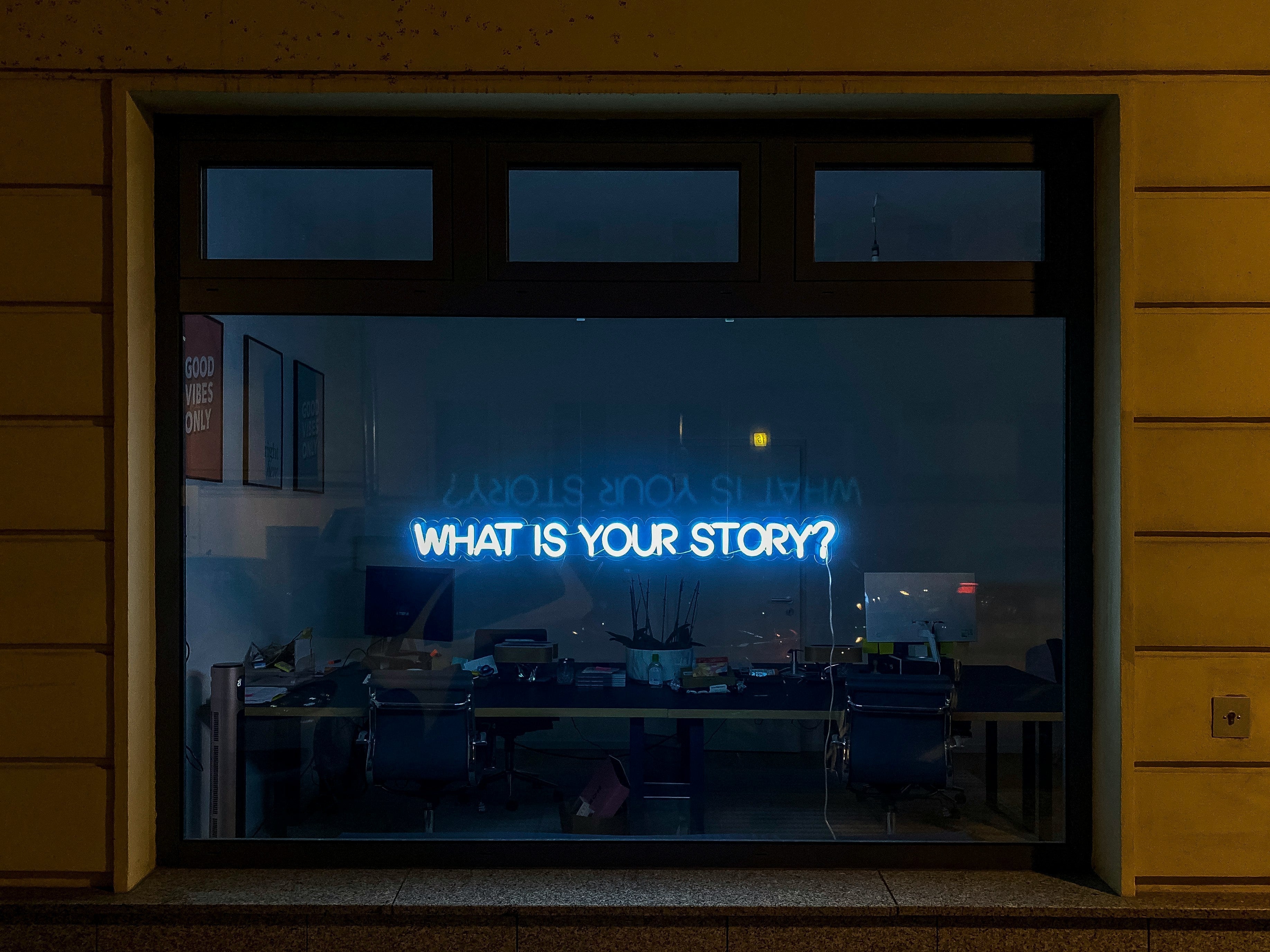 Neon sign on a window that asks, "What is Your Story?"