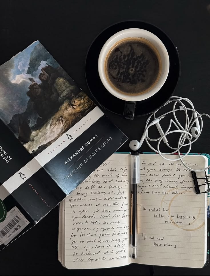 Photo of book, journal, wired headphones, and coffee cup